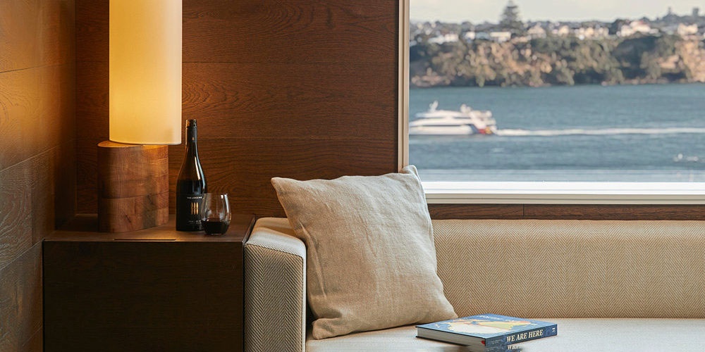 A sofa inside a hotel room with a view out to the Waitemata Harbour