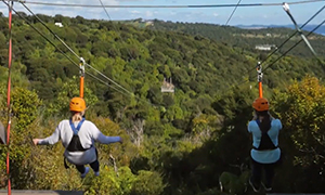 two people riding a EcoZip zipliner a tourism adventure in Auckland