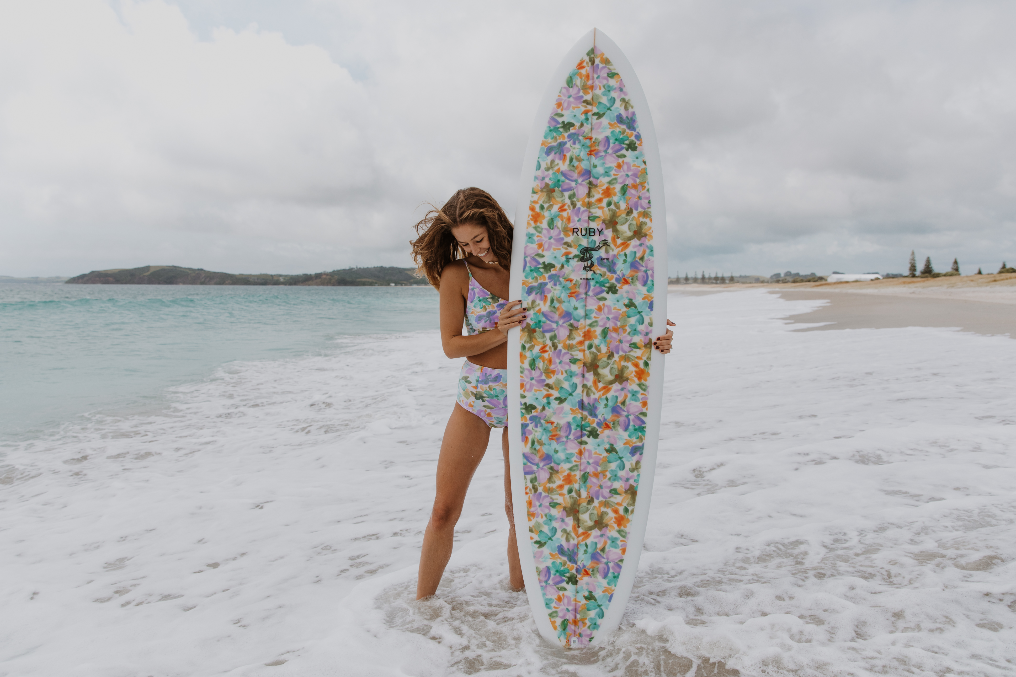 mODEL POSING WITH ruby BRANDED SURFBOARD ON BEACH