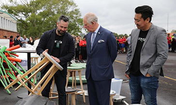 Man presenting Prince Charles with a stool that is made from recycled plastic