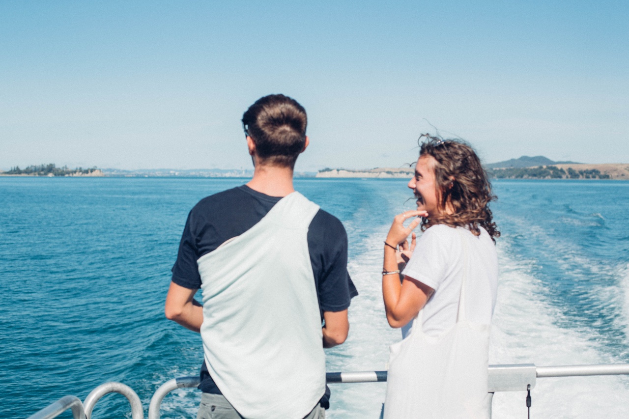 A young man and woman at the back of a ferry looking out to the water