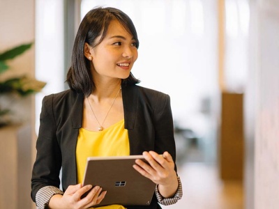 Woman wearing yellow shirt and black blazer holding tablet