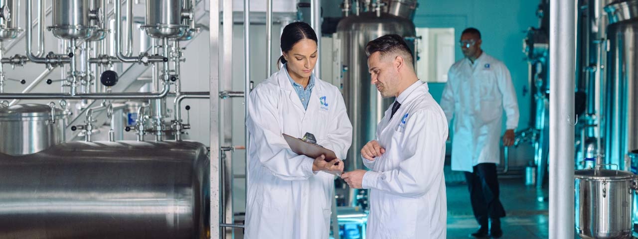 Two people in white lab coats looking at a clipboard