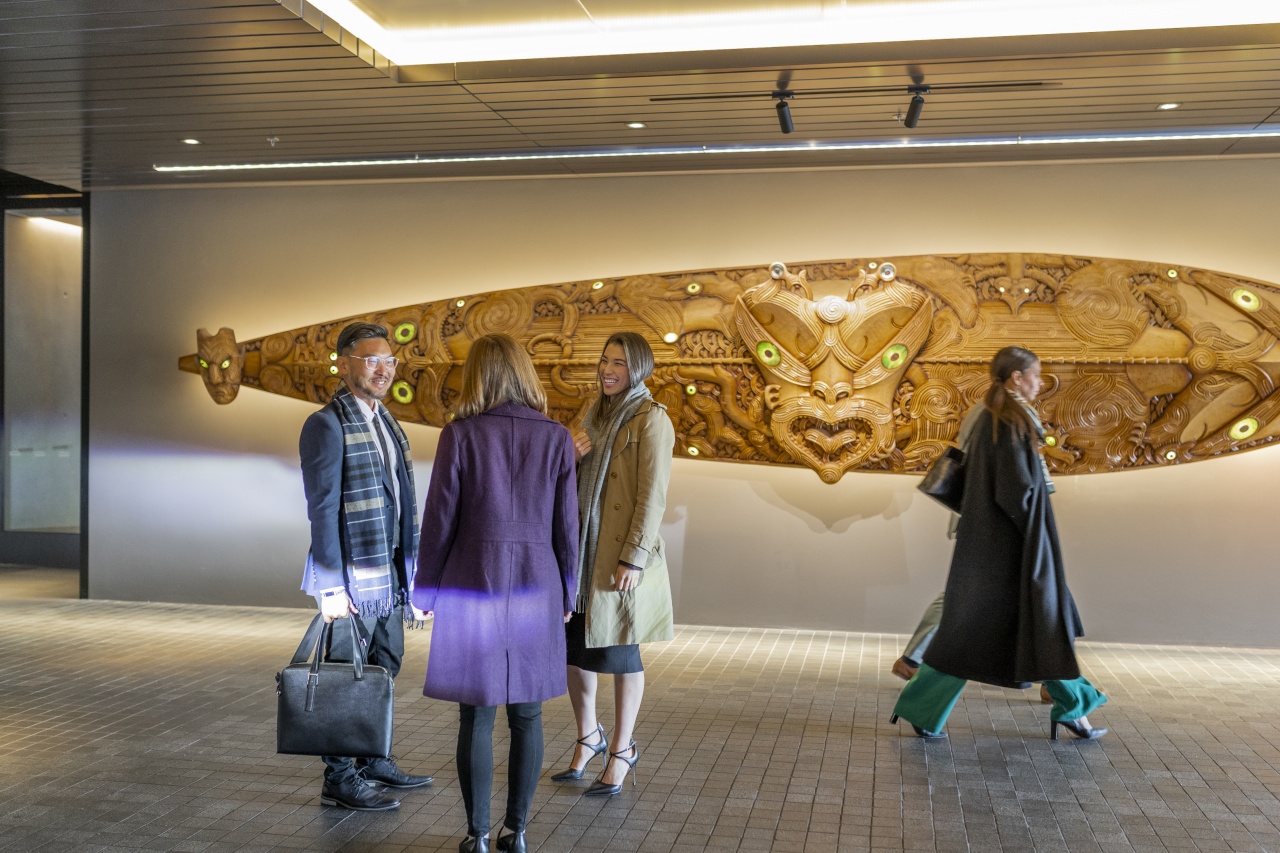 Delegates conversate in front of Maori artwork