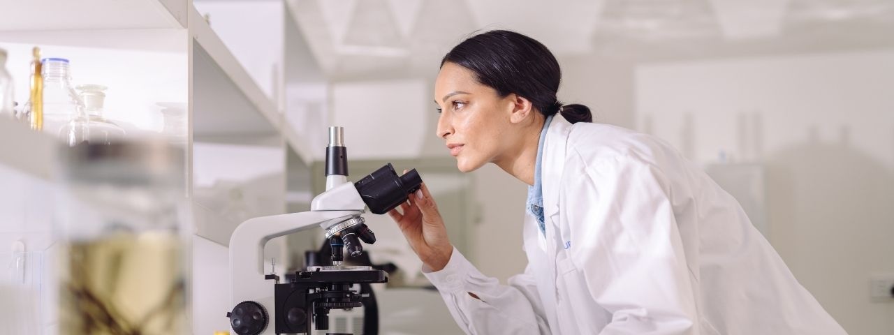 Woman working in research lab looking through microscope