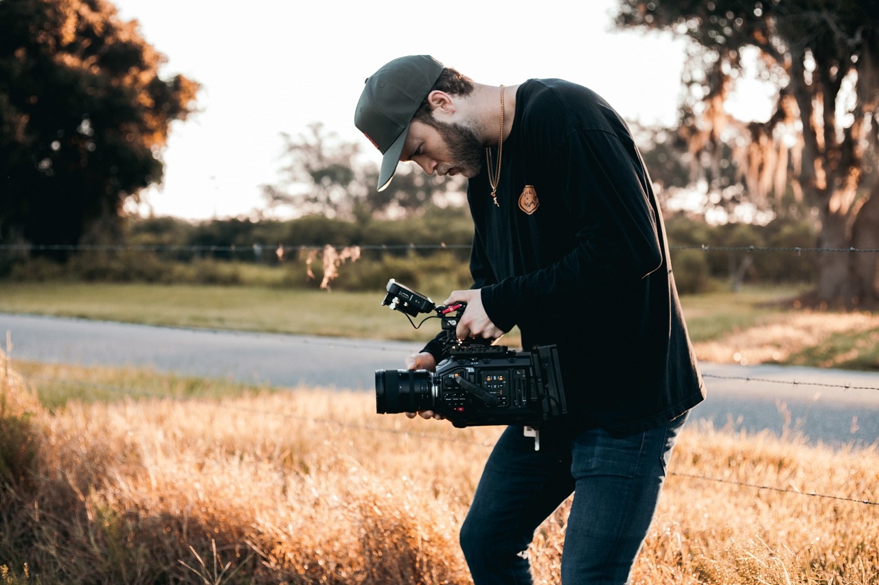 Man in black jacket and blue jeans holding a camera