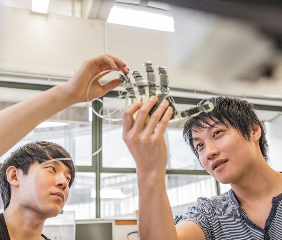 Tech Auckland - Culture - Two males discuss robot hand construction