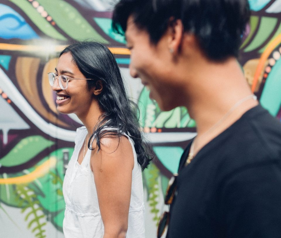 Tech Auckland - Commerce - Girl and boy smiling past Auckland-mural