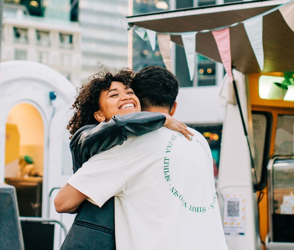 Tech Auckland - Place - People hugging outside food stalls in Auckland city