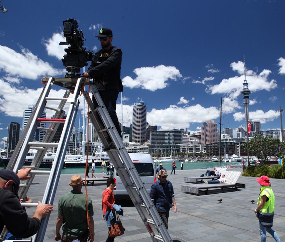 Camera man up a ladder filming a television show in Auckland city