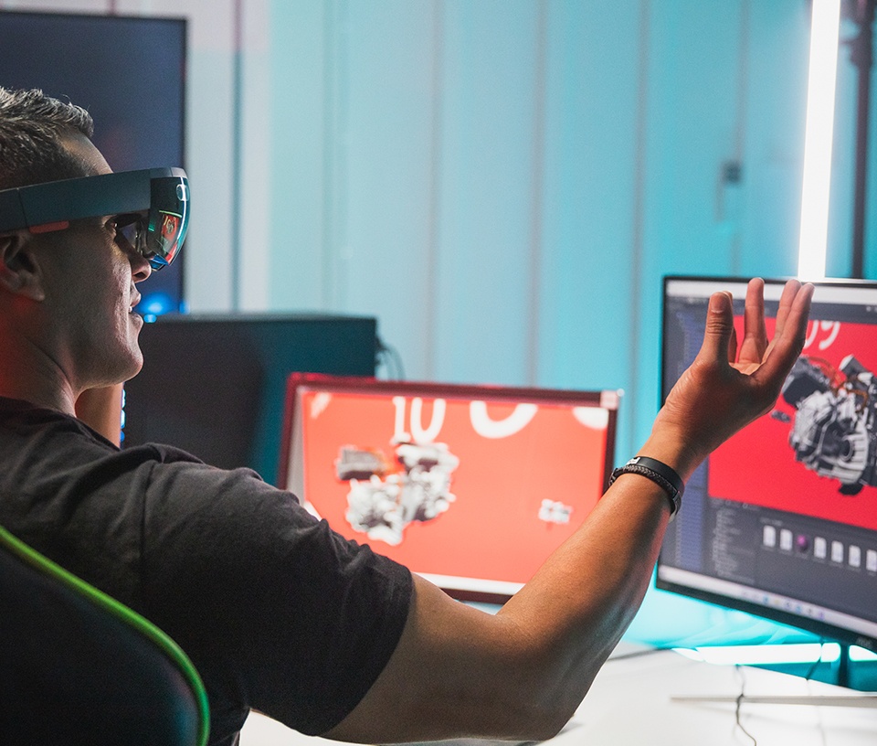 Man wearing virtual reality head set in front of computer screens