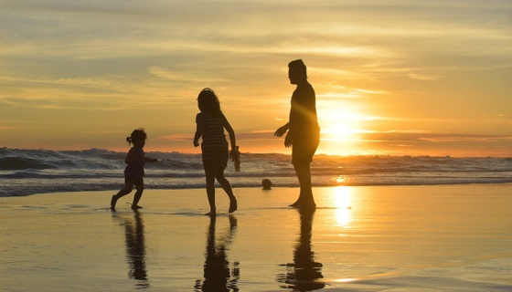 A family standing on a beach at sunset