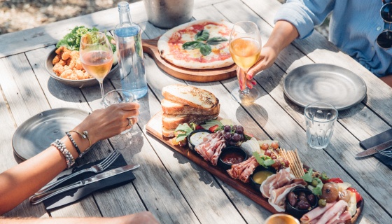 People sharing platters and pizza and drinking on Waiheke Island
