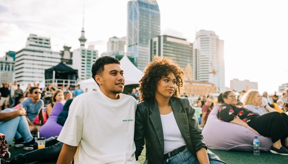 Two people sitting on the grass enjoying an outdoor event