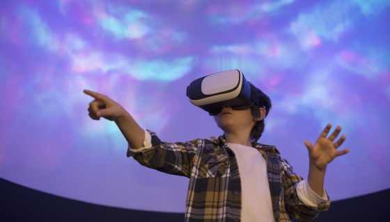 Boy pointing to sky with virtual reality headset on