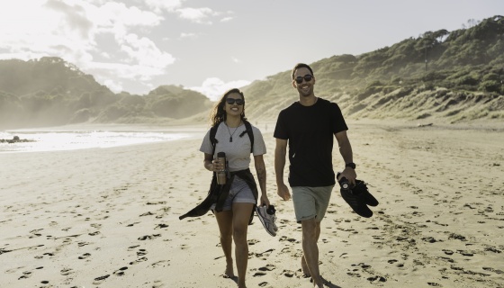 A man and a woman walking on the beach